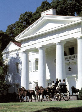 Outside view of the mansion at Morven Park, big white columns with horse and carriage crossing in front