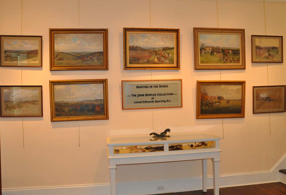 Exhibit room at the MHHNA with framed art on the walls and a display table.