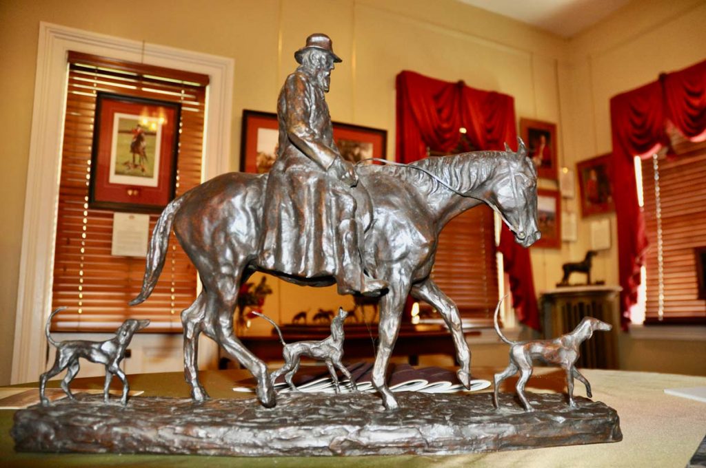 Bronze sculpture of an old man riding a horse with foxhounds around him on display at the MHHNA