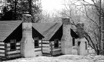 Black and white photo of old logo cabins with brick chimneys