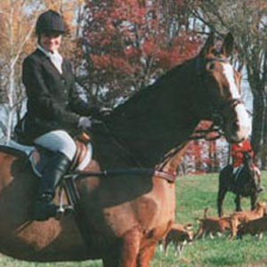 Janice Lee Ruetz in foxhunting attire on her horse in the field