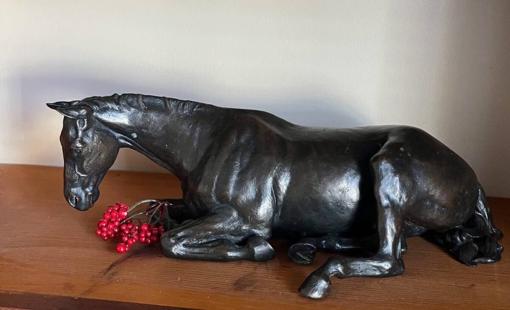 Bronze of horse laying down.