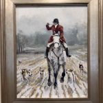 Huntsman blowing horn while cantering horse next to hounds