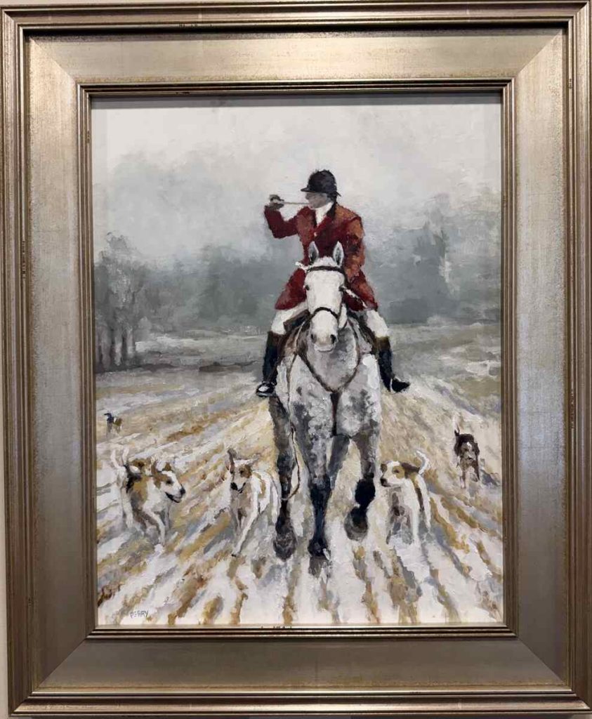 Huntsman blowing horn while cantering horse next to hounds
